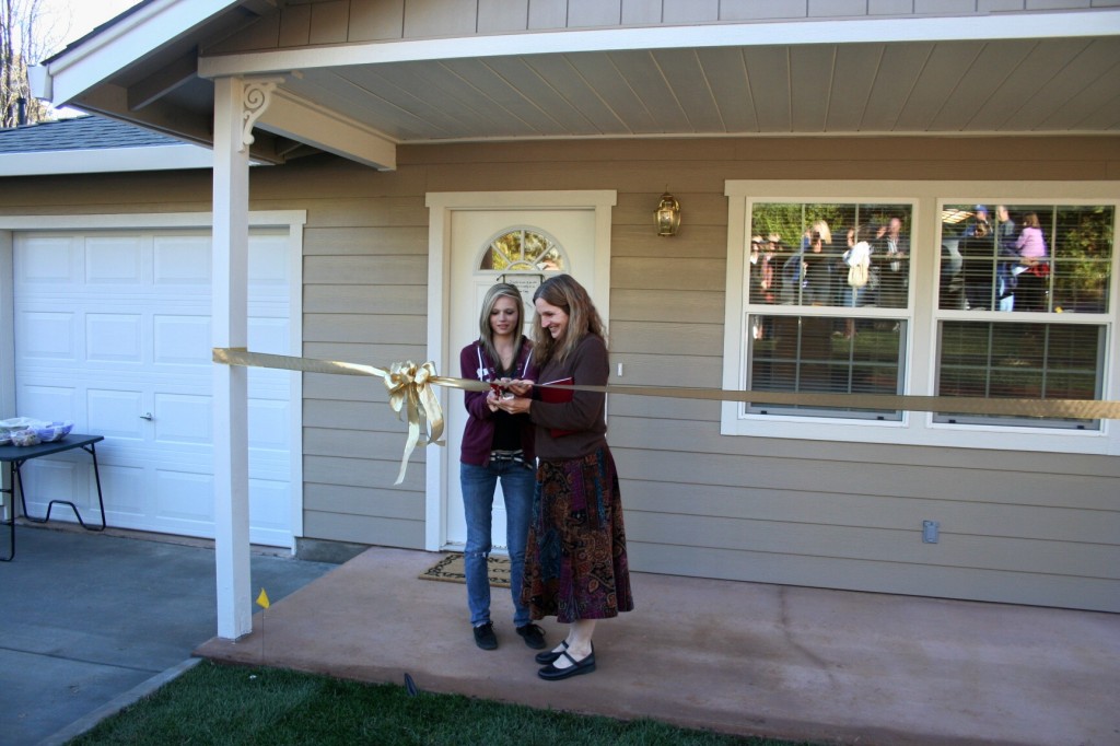 Family cutting their ribbon on the day of their home dedication ceremony